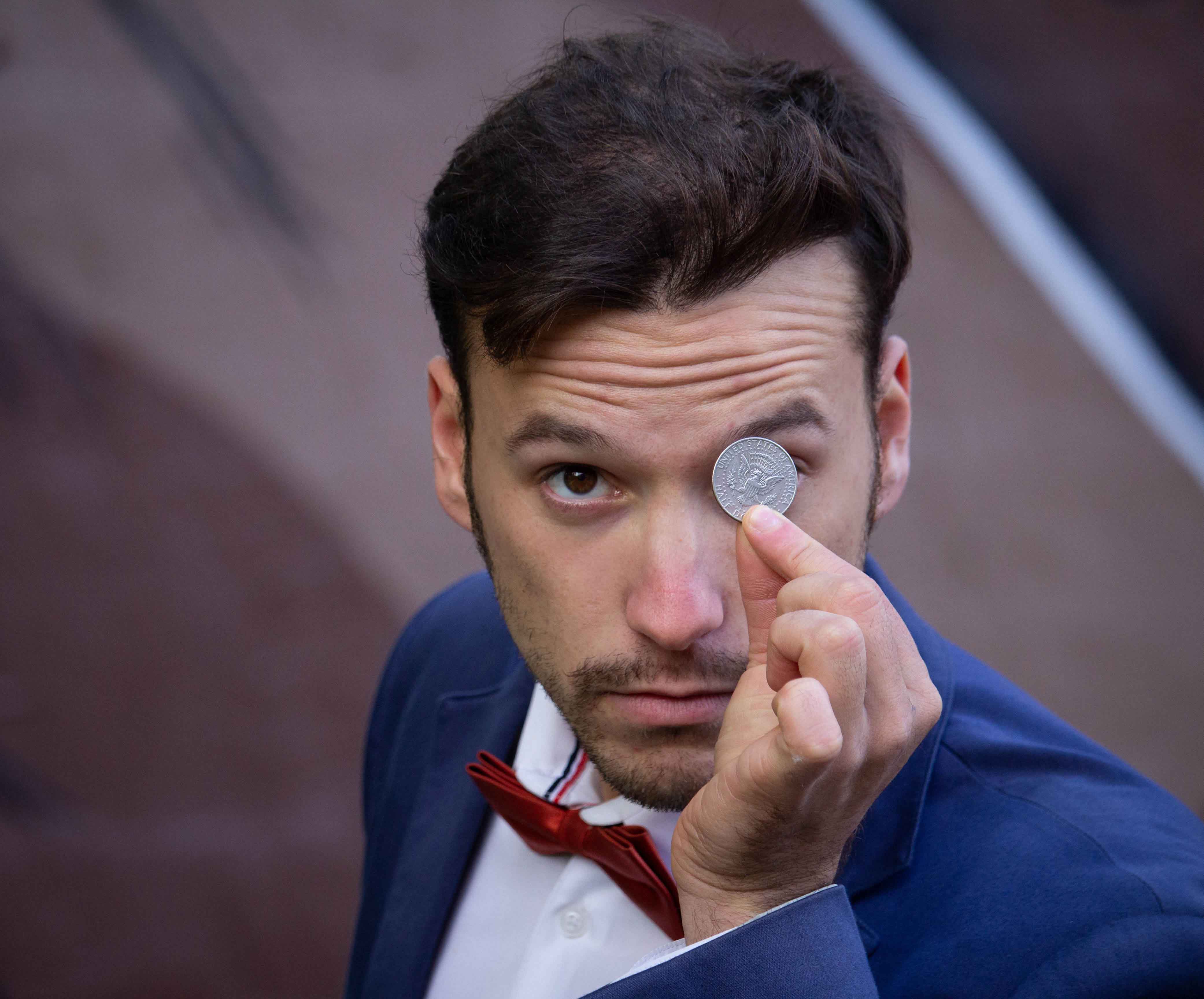 BigBong Photography: Magician in Suit Holding Coin with Intense Focus