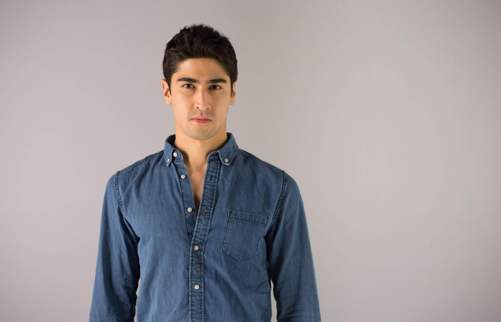 Portrait of BigBong, from his modelling portfolio, wearing a denim shirt in a studio white background.