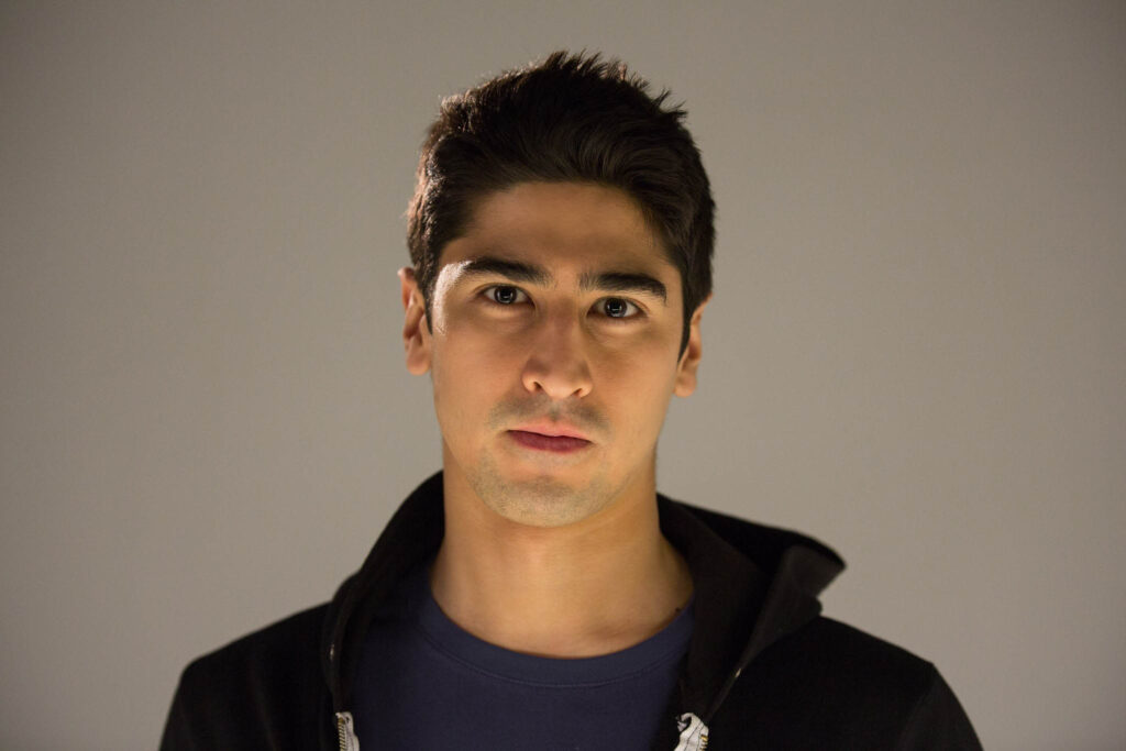 Portrait of BigBong wearing a black hoodie in a studio white background by Timothy Catchlove